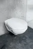 A white wall-mounted toilet in a modern bathroom with concrete-effect tiles. Produktbild-Vorschau