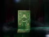 A green and gold deck of playing cards with the word 'WICKED' prominently displayed on the front, set against a dark, abstract background with green vertical lines and red hues. Náhled obrázku produktu