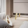 A close-up view of a white high-heeled shoe on a wooden floor, with a beige curtain and the legs of a piece of furniture in the background. Produktbild-Vorschau