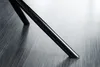 A close-up shot of a black chair leg on a textured gray floor. Produktbild-Vorschau