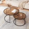 Two round coffee tables with brown glass tops and black metal frames are placed on a rug in front of a sofa. Náhľad obrázku produktu