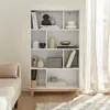 A white bookshelf with wooden legs, filled with decorative items and books, placed in a room with natural light coming from a window with sheer curtains. Produktbild-Vorschau