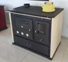 A beige and black wood-burning stove with a yellow kettle on top, placed on a tiled floor. Voir les images du produit