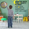 A young boy is playing darts in a room with a dartboard on the wall. Voir les images du produit