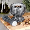 A marble mortar and pestle with peppercorns and a jug of olive oil on a wooden cutting board. Voir les images du produit