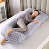 A woman is sleeping on a large U-shaped pillow in a bedroom. Náhled obrázku produktu