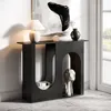 A modern black console table with arched cutouts, decorated with a lamp, books, a vase, and a sculptural head. Produktbild-Vorschau