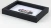 A black wooden picture frame with a picture of a woman inside, placed on a white surface. Produktbild-Vorschau