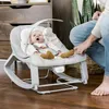 A baby is sitting in a rocking chair while an adult's legs are visible next to it. Produktbild-Vorschau