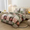 A neatly made bed with a patchwork-style duvet cover and pillows in a bedroom setting. Náhled obrázku produktu