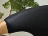 A close-up of a black leather chair armrest with a wooden base, with a blurred green plant in the background. Voir les images du produit