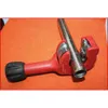 A red pipe cutter with a silver pipe is placed on an orange surface. Anteprima dell’immagine prodotto