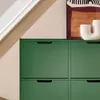 A close-up view of a dark green cabinet with multiple drawers and a piece of abstract art and a white vase on top. Náhľad obrázku produktu