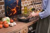A person is cooking in a kitchen with a decorative panel behind the stove. Náhľad obrázku produktu