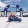 A blue Sparco shoe is placed on a paved surface in front of a blurred blue archway with the Sparco logo. Produktbild-Vorschau
