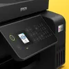 Close-up of the control panel and side of a black Epson printer against a yellow background. Produktbild-Vorschau