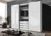 A modern bedroom or living room setting with a large white sliding door wardrobe featuring an integrated TV element. The wardrobe is placed against a textured black wall, with a large window showing a cityscape on the left. A coffee table with decorative i Anteprima dell’immagine prodotto