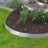 A garden bed with metal edging, surrounded by grass and plants. Produktbild-Vorschau