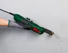 A hand wearing a glove holds a green and black multi-tool against a textured gray wall, with the tool's copper end touching the wall. Produktbild-Vorschau