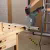 A person is using an angle grinder to cut a metal pipe on a workbench. Produktbild-Vorschau