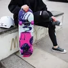 A person sitting on a concrete ledge at a skatepark, holding a skateboard. Voir les images du produit
