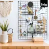 A desk with a wall grid decorated with photos, stars, and decorative items. Produktbild-Vorschau