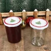 Two jars with Christmas-themed lids are placed on a wooden surface, with miniature Christmas trees and ornaments in the background. Anteprima dell’immagine prodotto