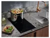 A modern kitchen countertop with a cooking pot on an induction hob, a sink, and a faucet. Produktbild-Vorschau