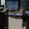 A close-up shot of a socket wrench bit engaging with a screw on a black metal object. Produktbild-Vorschau