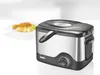 A deep fryer is shown in front of a plate of food on a white background. Produktbild-Vorschau