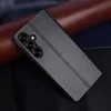 A black flip phone case is shown diagonally on a dark surface with rolls of brown and dark blue material behind it. Produktbild-Vorschau