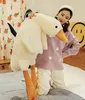 A woman is holding a large plush duck toy in a bedroom setting. Podgląd zdjęcia produktu