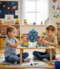 Two children are building a flower bouquet from toy bricks at a low table in a room that appears to be a playroom or classroom. Náhľad obrázku produktu