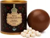 A chocolate sphere and marshmallows next to a tin of hot chocolate mix. Produktbild-Vorschau