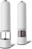Two white electric pepper grinders are shown side-by-side against a white background. The grinder on the right is filled with peppercorns. Podgląd zdjęcia produktu
