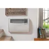 A white electric heater is mounted on a white wall next to a window with books on the windowsill. Produktbild-Vorschau