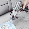A hand is holding a portable vacuum cleaner and cleaning a car interior. Produktbild-Vorschau