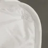A close-up view of a white fabric product, showing a snap closure detail. Produktbild-Vorschau