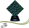 A dark green, geometric 3D wall panel is displayed on a digital scale, with icons of a hand holding a feather at the bottom left. Podgląd zdjęcia produktu