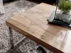 A close-up view of a wooden coffee table with a metal frame, placed on a fluffy rug. Produktbild-Vorschau