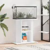 A white aquarium stand with an aquarium on top, placed in a room with a plant and a shelf unit. Náhľad obrázku produktu
