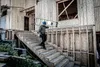 A construction worker carries a ladder up a set of wooden stairs at a building site. Podgląd zdjęcia produktu