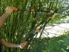 A person is using a pair of long-handled loppers to prune a tree branch. Produktbild-Vorschau