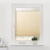A cream-colored pleated blind is installed on a white window frame. The blind covers most of the window, with a small clear section at the top and bottom. A small potted plant sits on the windowsill. Produktbild-Vorschau