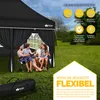 A family is sitting under a black pop-up pavilion in a grassy outdoor setting. Produktbild-Vorschau
