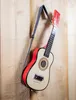 A toy guitar is hanging on a wooden wall. Anteprima dell’immagine prodotto