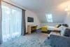 A hotel room with a bed, sofa, desk, and TV. Produktbild-Vorschau