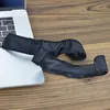 Two black ear pads are placed on a wooden surface next to a laptop. Náhled obrázku produktu
