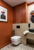 A modern bathroom with a toilet, sink, and artwork. Podgląd zdjęcia produktu