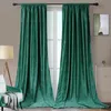 Two dark teal velvet curtains are shown hanging from a curtain rod in front of a window. A floor lamp and a chair are visible to the left, and a dresser with a small plant and artwork is visible to the right.